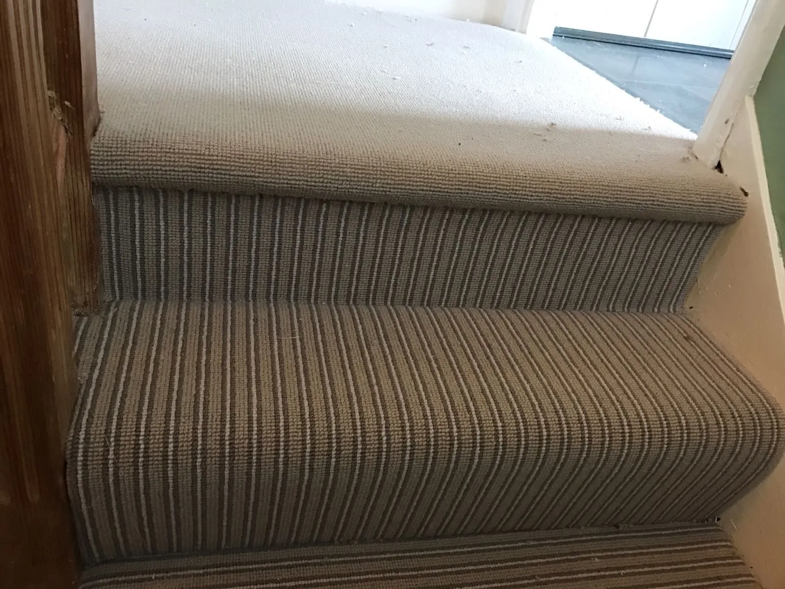 Beige striped stair carpet close-up fitting with subfloor and underlay preparation