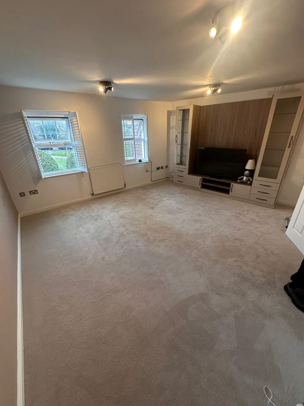 Lounge with fitted TV and storage unit showing existing worn carpet before uplift — Bromley BR1