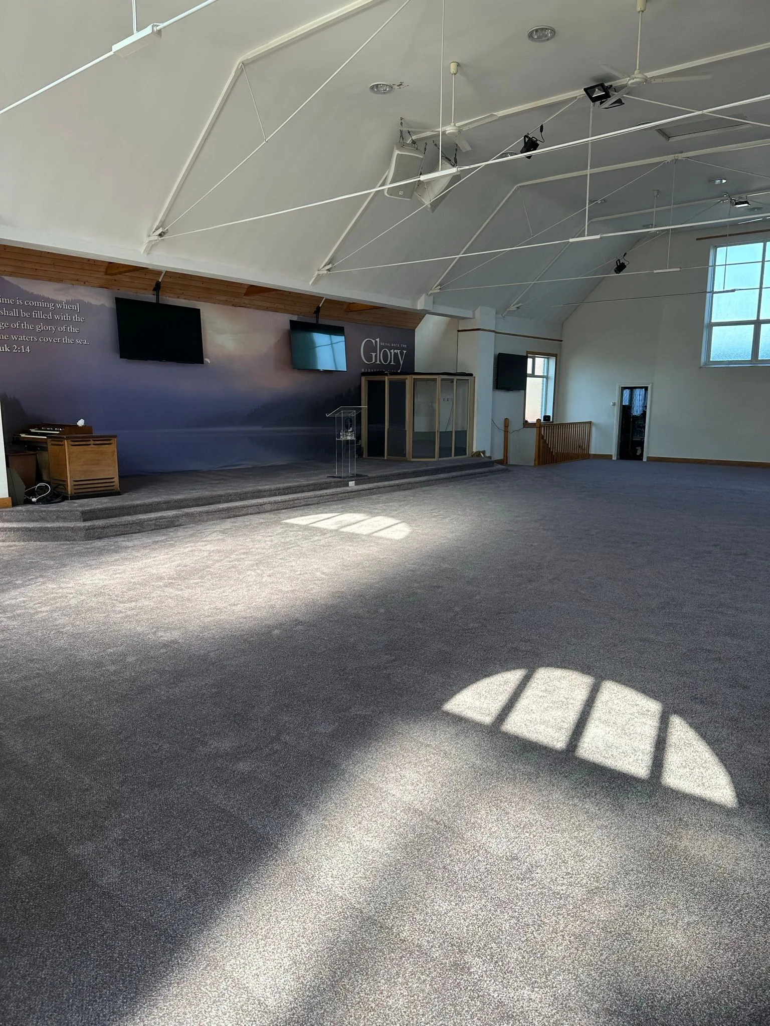 Wide-angle view of completed dark grey carpet fitted in a church hall — large commercial carpet installation