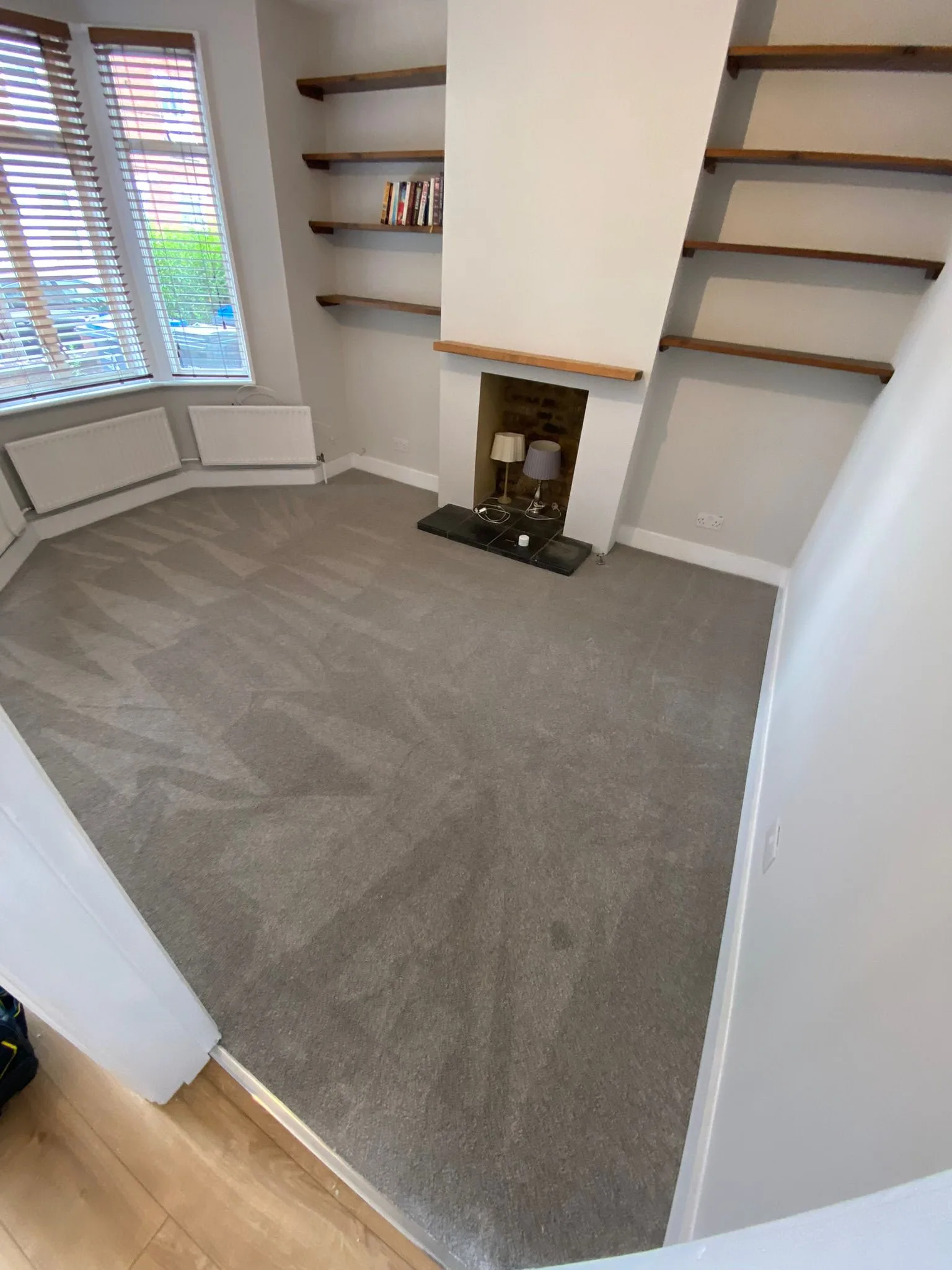 New grey carpet fitted in a residential living room with bay window and fireplace