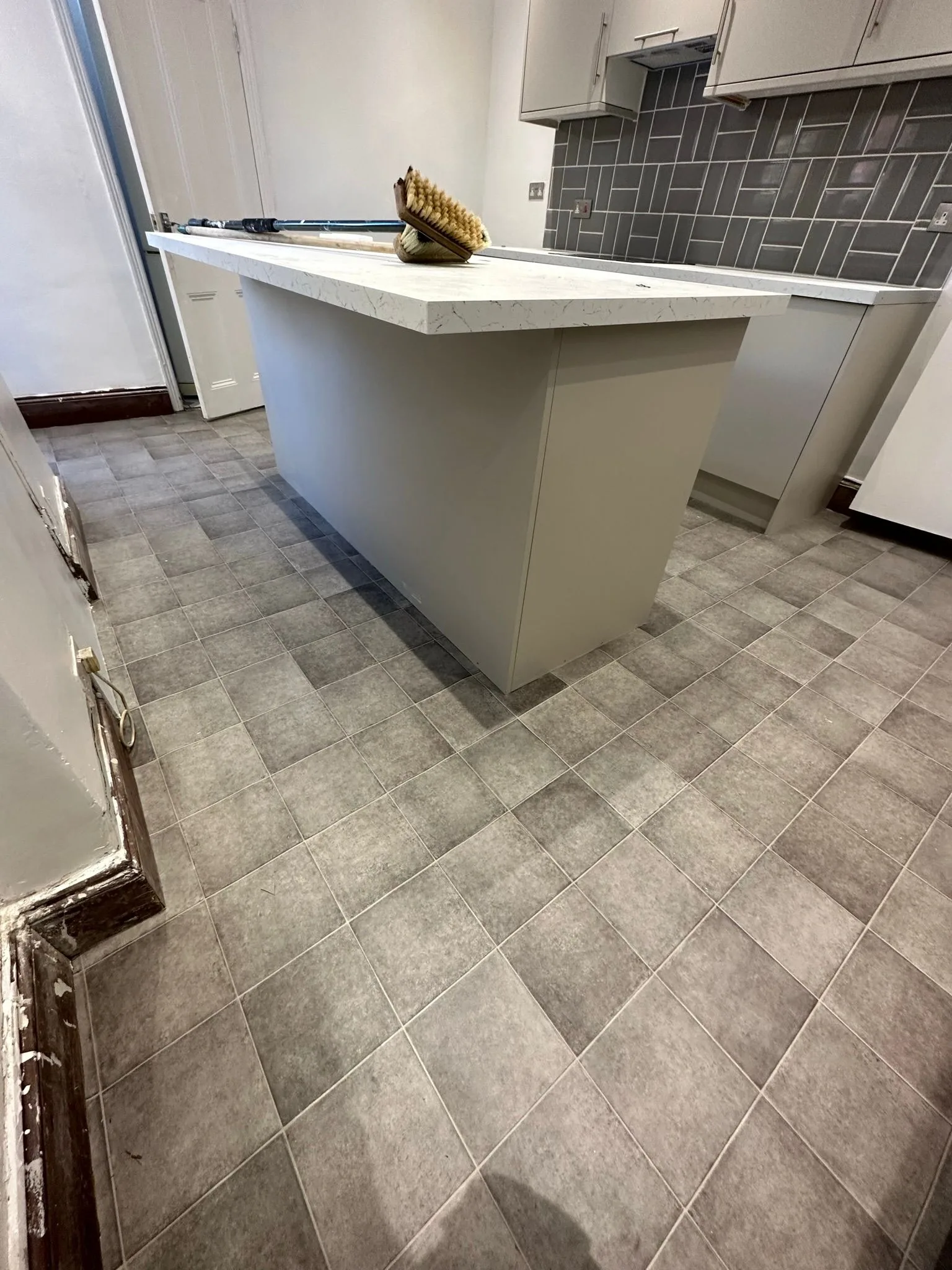Grey concrete-effect vinyl flooring in a kitchen, a covering that can hide trapped subfloor moisture