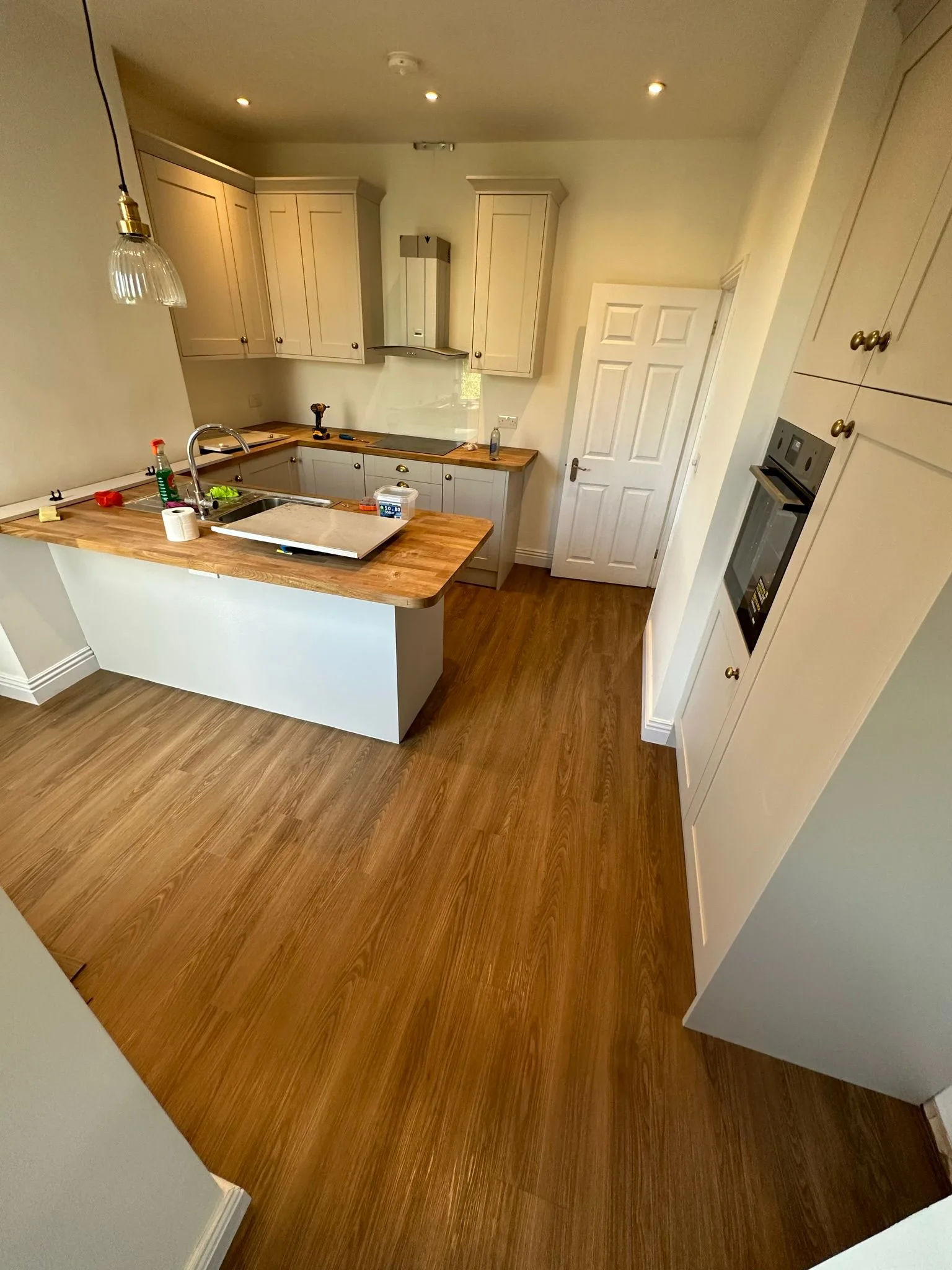 Warm oak-effect LVT flooring fitted in a modern kitchen with grey Shaker-style units