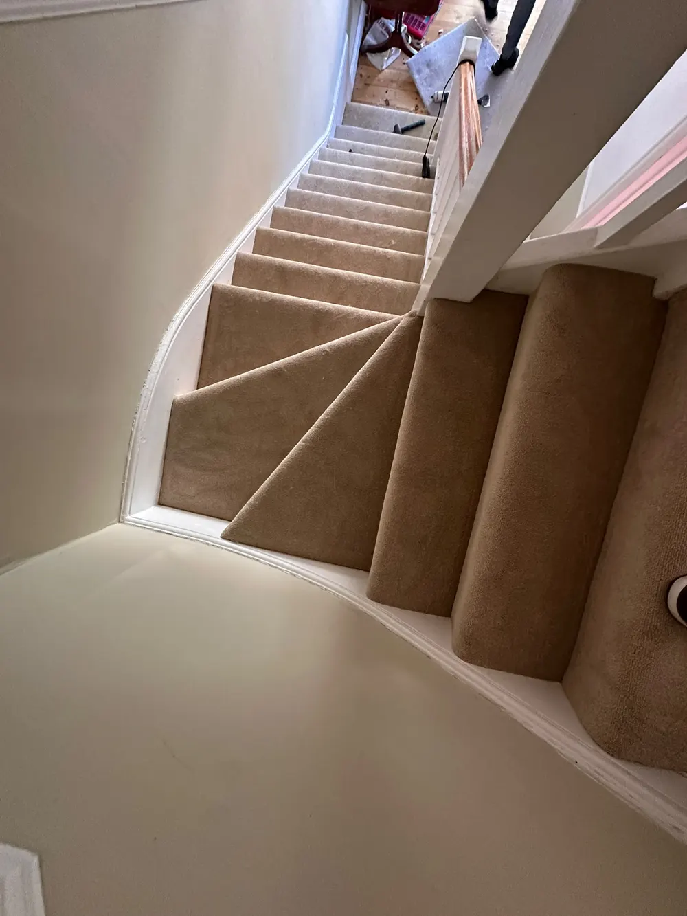 Top-down view of new carpet neatly cut and fitted around the winder steps on the stairs — South Croydon